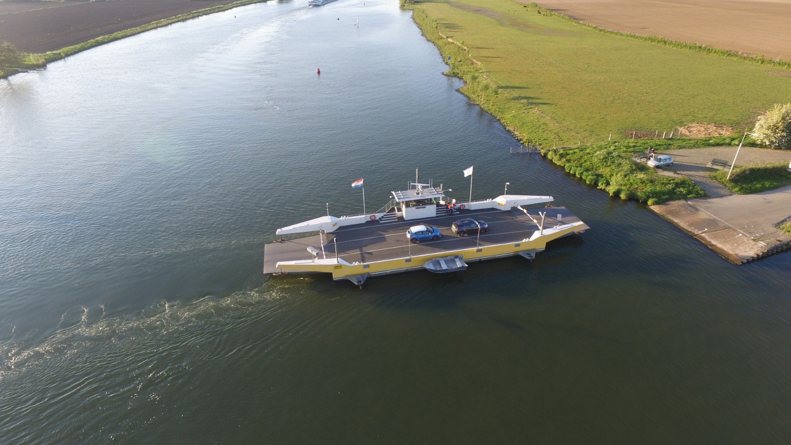 De Festina Lente steekt met auto's aan boord de Maas over, gezien vanuit de lucht